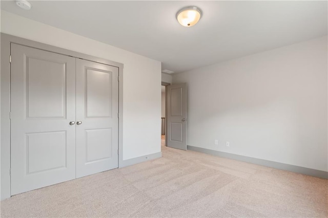 unfurnished bedroom featuring light carpet and a closet