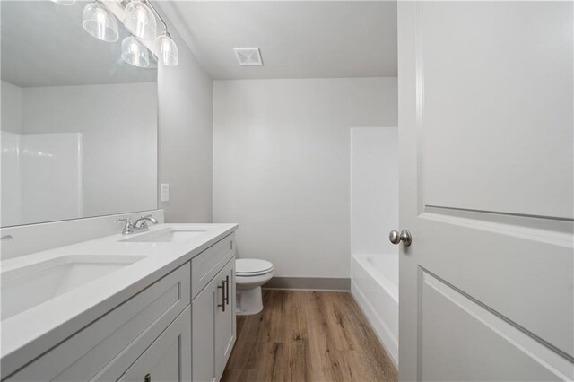 full bathroom with vanity, hardwood / wood-style floors, washtub / shower combination, and toilet