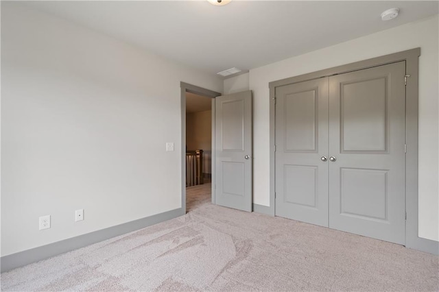 unfurnished bedroom with light colored carpet and a closet