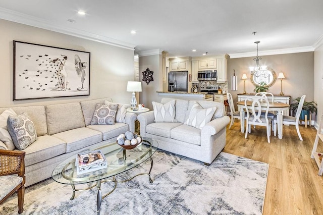 living area with light wood finished floors, baseboards, ornamental molding, and an inviting chandelier