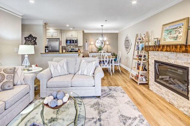 living area with light wood-style flooring, crown molding, a fireplace, baseboards, and an inviting chandelier