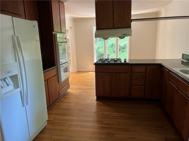 4968 Twin Branches Way, Dunwoody, GA 30338 - kitchen featuring appliances with stainless steel finishes, under cabinet range hood, wood finished floors, dark countertops, and ornamental molding