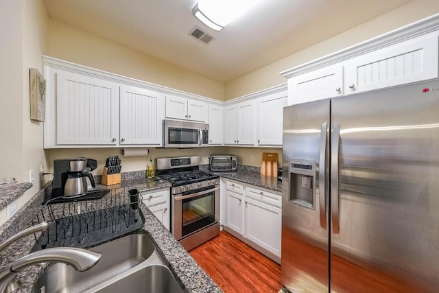 kitchen with light wood-style floors, white cabinets, stainless steel appliances, and visible vents