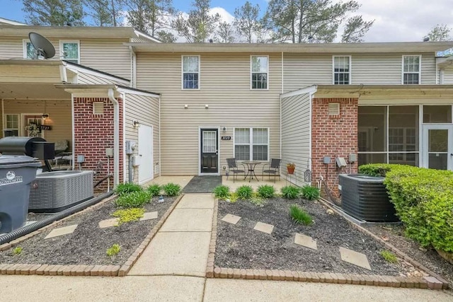 back of property with a sunroom, central AC, a patio area, and brick siding