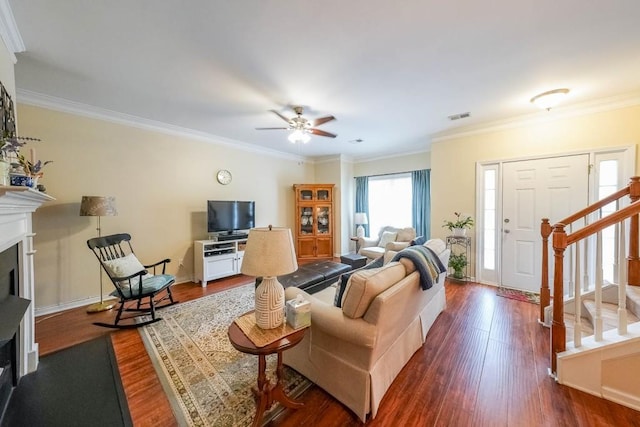 living area with visible vents, crown molding, stairs, a fireplace, and dark wood-style floors