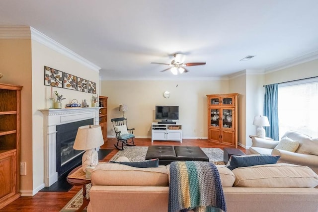 living area with visible vents, a ceiling fan, dark wood-style flooring, and ornamental molding