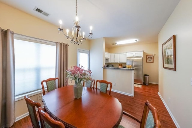 dining space with baseboards, visible vents, an inviting chandelier, and dark wood-type flooring