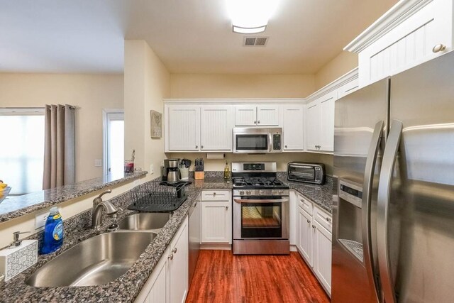 kitchen with visible vents, dark wood-style flooring, a toaster, a sink, and appliances with stainless steel finishes