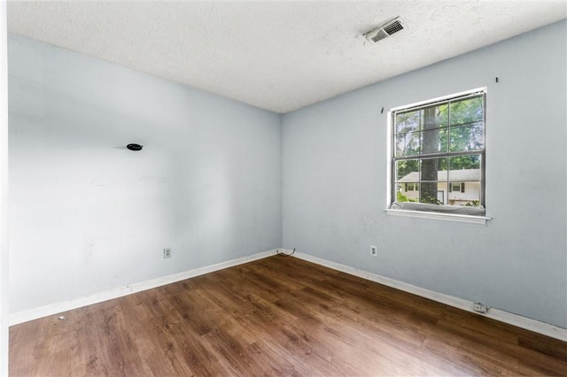 unfurnished room with wood finished floors, baseboards, and a textured ceiling