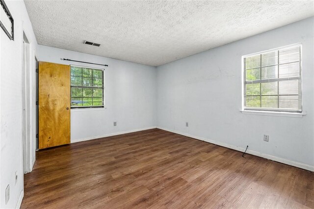 unfurnished room featuring wood finished floors, a textured ceiling, and baseboards