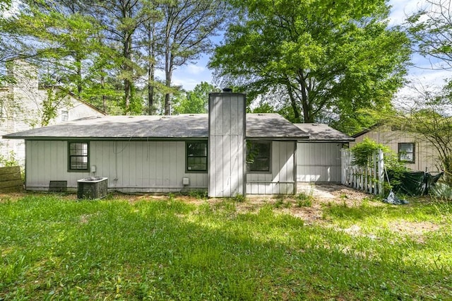 back of property featuring a chimney, fence, and central AC unit