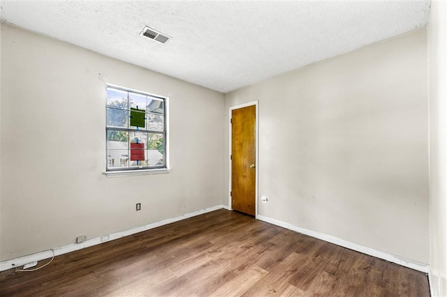 empty room with wood finished floors, baseboards, and a textured ceiling