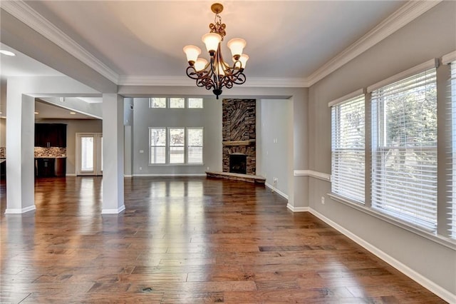 unfurnished living room featuring a chandelier, a stone fireplace, ornamental molding, and dark hardwood / wood-style flooring