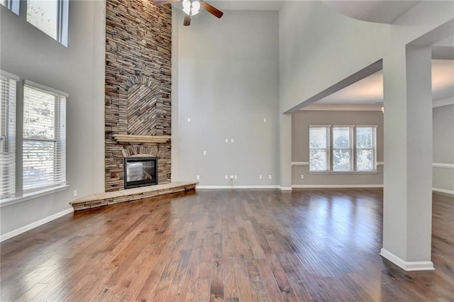 unfurnished living room featuring a towering ceiling, a wealth of natural light, and a stone fireplace