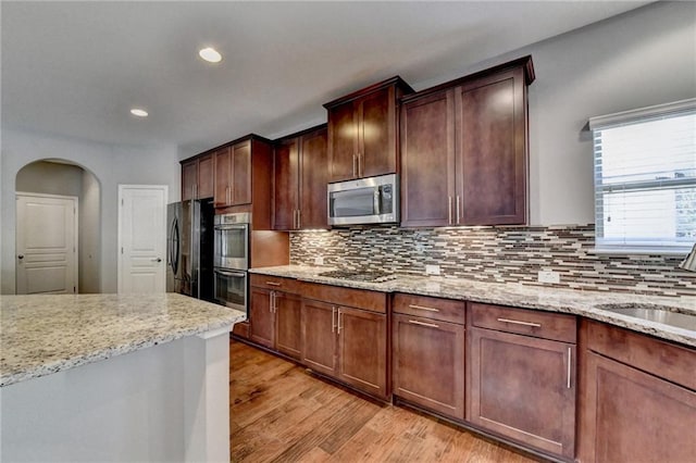 kitchen with light stone countertops, sink, stainless steel appliances, and tasteful backsplash