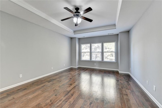 unfurnished room with ceiling fan, dark wood-type flooring, a tray ceiling, and ornamental molding