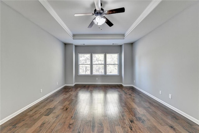 empty room with ornamental molding, dark hardwood / wood-style flooring, ceiling fan, and a raised ceiling