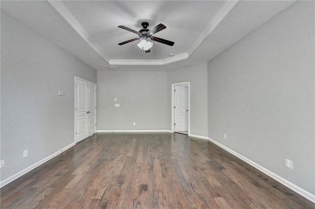 empty room featuring ceiling fan, dark wood-type flooring, ornamental molding, and a raised ceiling