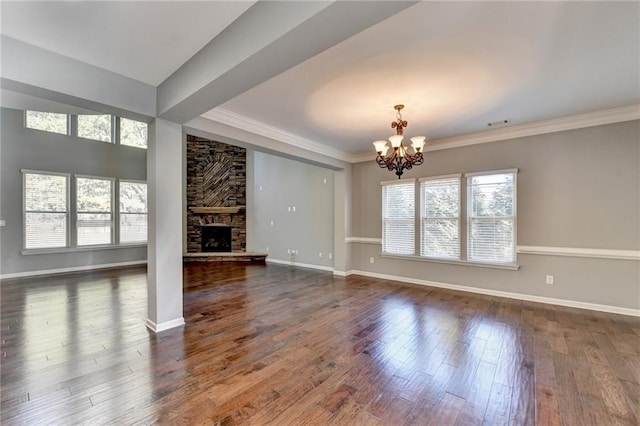 unfurnished living room featuring dark hardwood / wood-style flooring, crown molding, a stone fireplace, and an inviting chandelier