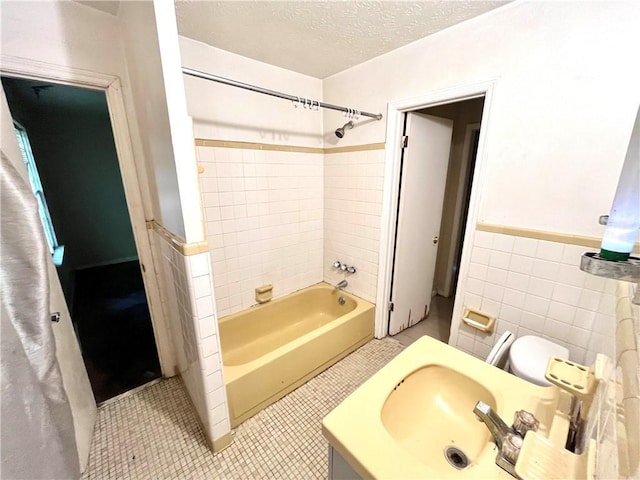 full bathroom with sink, tile walls, tile patterned flooring, tiled shower / bath combo, and a textured ceiling