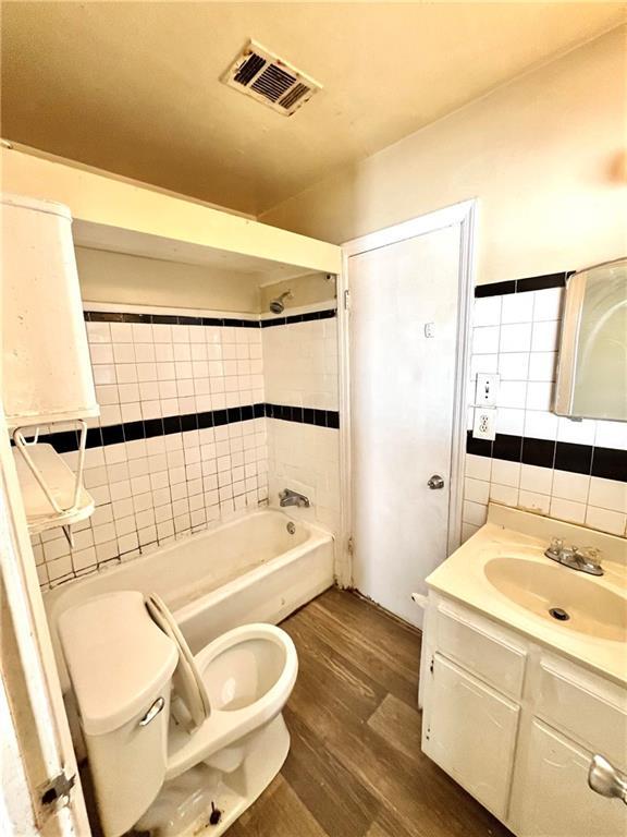 bathroom featuring tile walls, hardwood / wood-style floors, toilet, and a healthy amount of sunlight