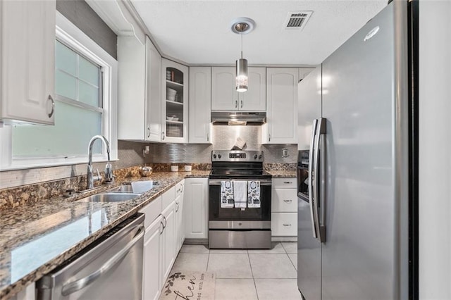 kitchen featuring a sink, stainless steel appliances, under cabinet range hood, visible vents, and stone countertops