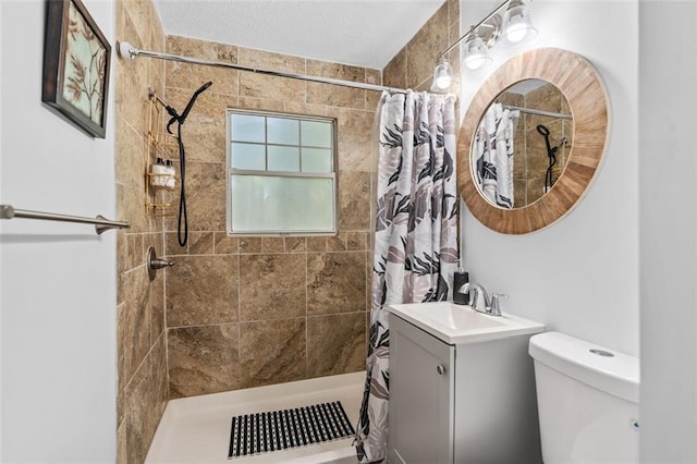 full bathroom with toilet, a tile shower, and vanity