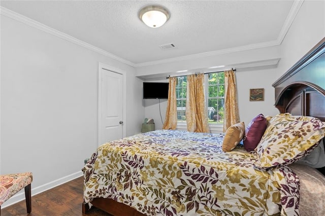 bedroom featuring visible vents, baseboards, ornamental molding, a textured ceiling, and wood finished floors