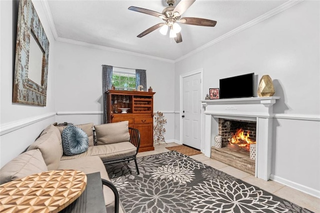 tiled living room with a ceiling fan, ornamental molding, a warm lit fireplace, and baseboards