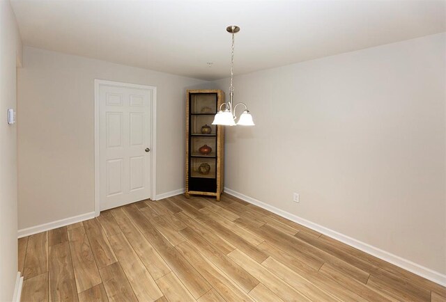 unfurnished dining area with hardwood / wood-style flooring and a chandelier