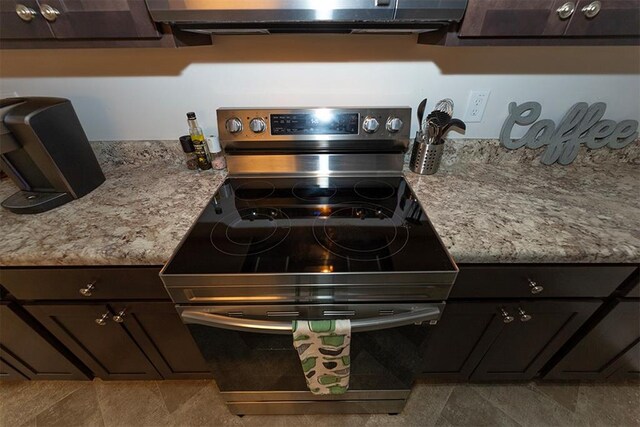 kitchen featuring dark brown cabinets, light stone counters, and stainless steel range with electric cooktop