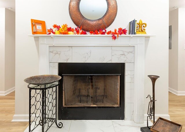 interior details featuring a tiled fireplace and wood-type flooring