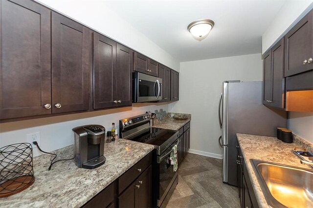 kitchen featuring light stone countertops, appliances with stainless steel finishes, sink, and dark brown cabinetry