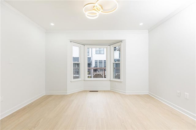 unfurnished room featuring baseboards, visible vents, ornamental molding, and wood finished floors