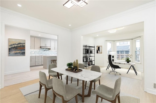 dining area featuring baseboards, ornamental molding, and light wood-style flooring