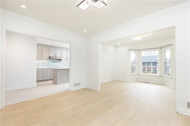 unfurnished living room with visible vents, ornamental molding, baseboards, and light wood-type flooring