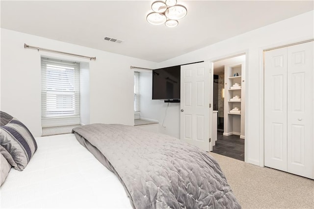 carpeted bedroom with connected bathroom and visible vents