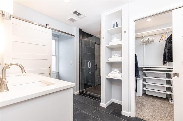 bathroom featuring a walk in closet, built in shelves, baseboards, visible vents, and a stall shower