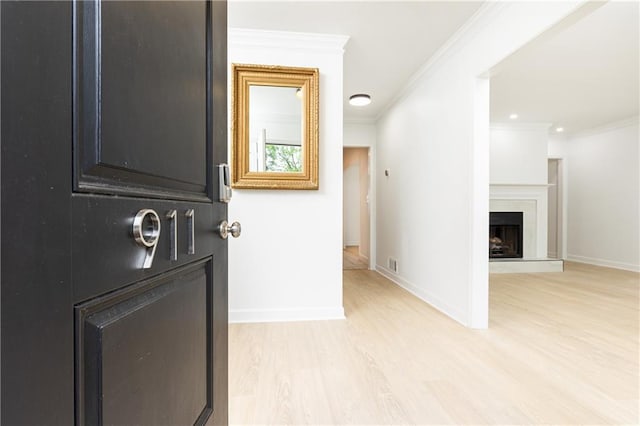 corridor with baseboards, visible vents, ornamental molding, and light wood-style flooring