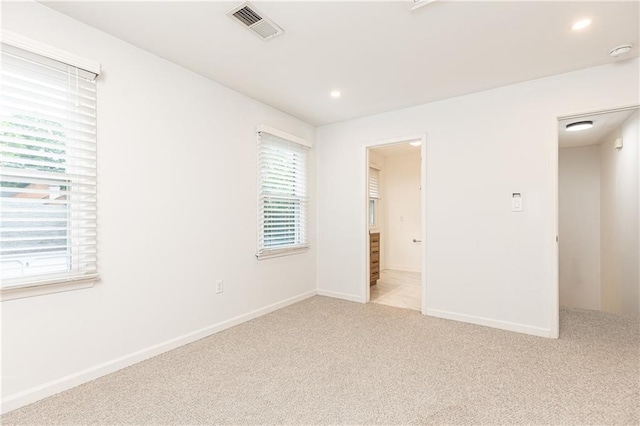 spare room with baseboards, light carpet, recessed lighting, and visible vents