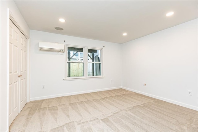 unfurnished bedroom featuring recessed lighting, baseboards, light colored carpet, and a wall mounted air conditioner
