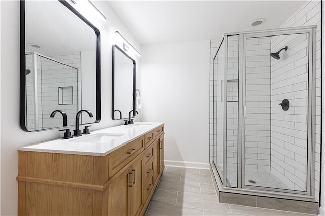 bathroom featuring a sink, baseboards, a shower stall, and double vanity