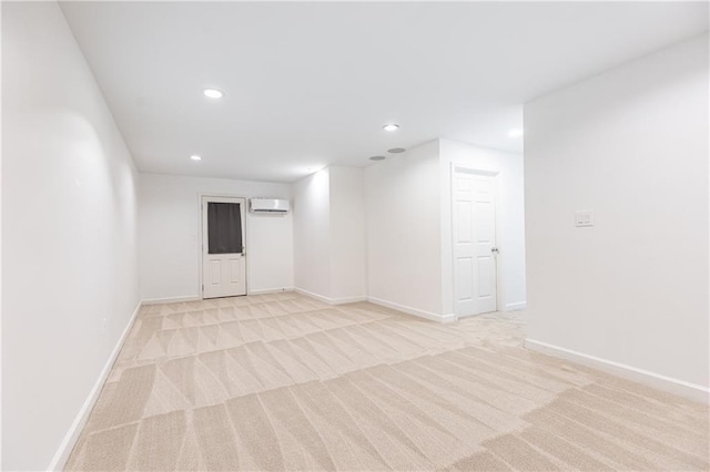 empty room featuring recessed lighting, a wall mounted air conditioner, baseboards, and light colored carpet