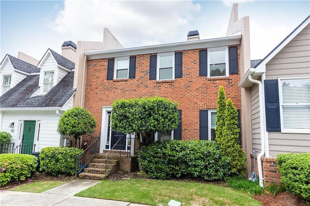 view of front of property featuring a chimney and brick siding