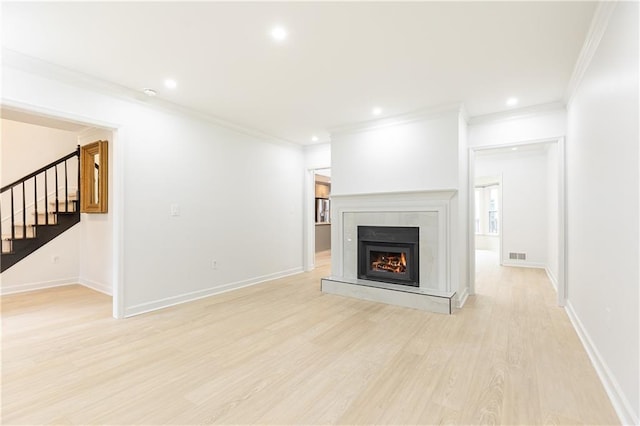 unfurnished living room featuring crown molding, visible vents, light wood finished floors, and stairway