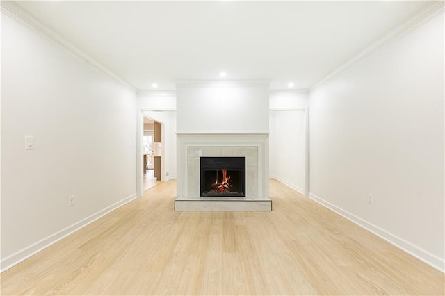 unfurnished living room with recessed lighting, crown molding, a lit fireplace, and light wood finished floors