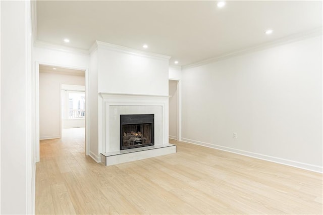 unfurnished living room featuring ornamental molding, a fireplace with raised hearth, recessed lighting, and light wood-style flooring