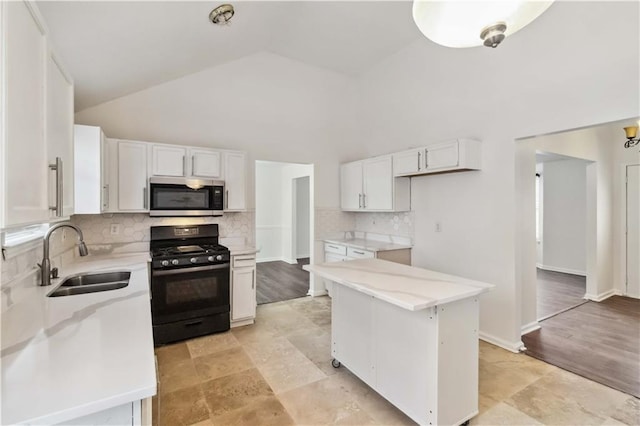 kitchen with black range with gas cooktop, sink, white cabinetry, and backsplash