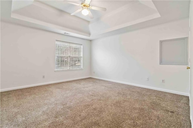 spare room with ceiling fan, carpet flooring, and a raised ceiling