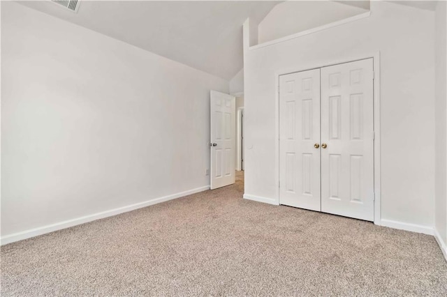 unfurnished bedroom featuring a closet, lofted ceiling, and carpet